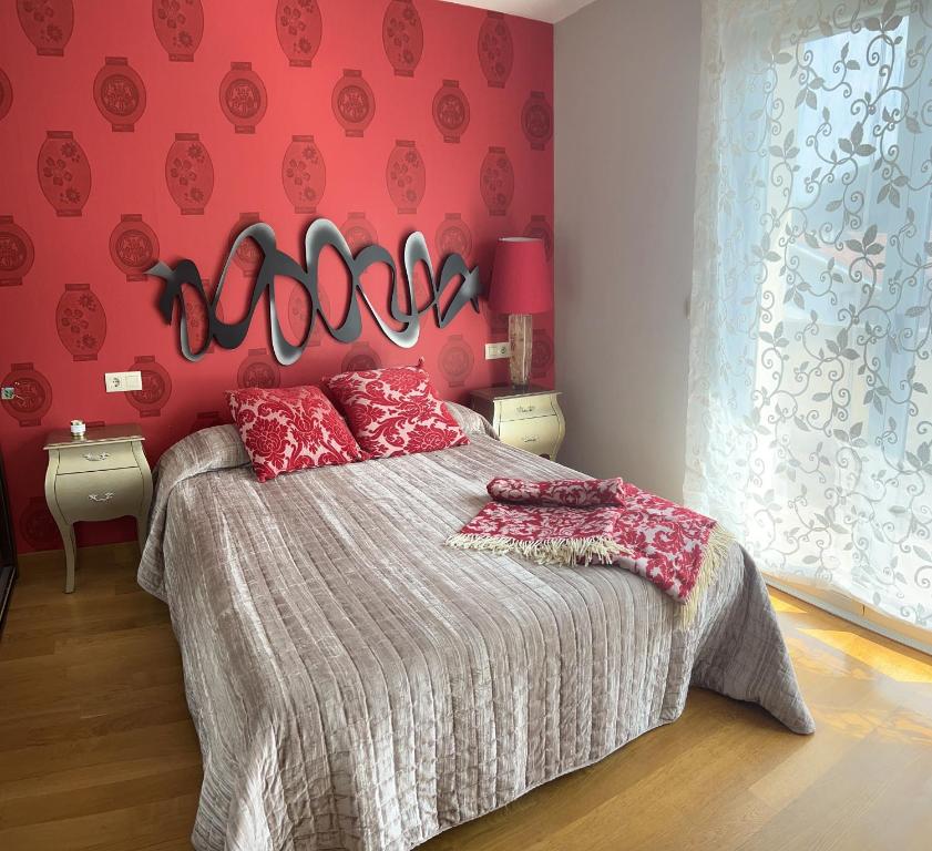 a bedroom with a bed with a red wall at La Casa de Blanca in Candás