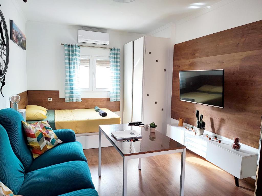 Una sala de estar con un sofá azul y una mesa. en Bright and quiet studio in Málaga, en Málaga