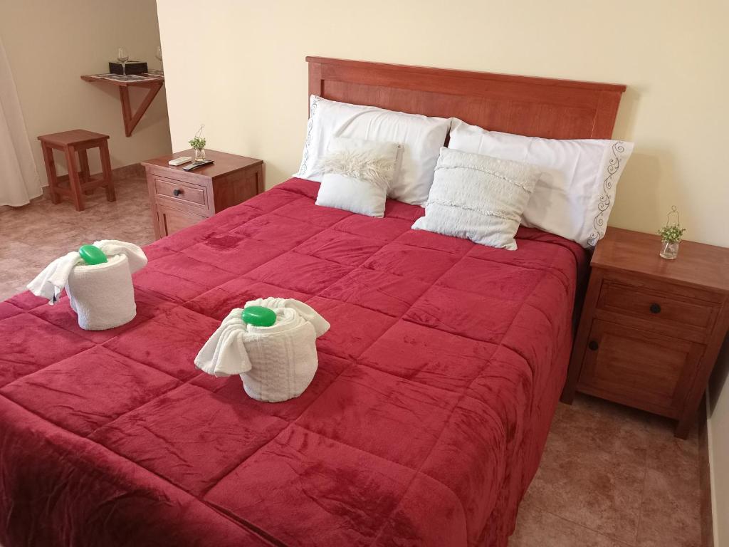 Un dormitorio con una cama roja con toallas. en El Tonel en Cafayate