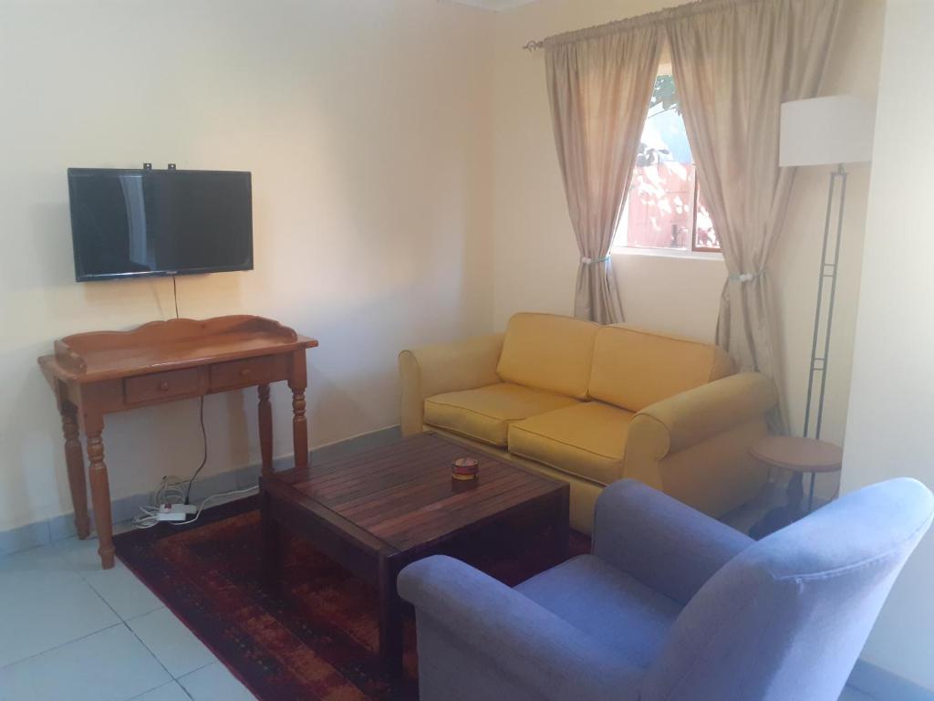 a living room with a couch and a table and a tv at Carol Cottage Fun in Johannesburg