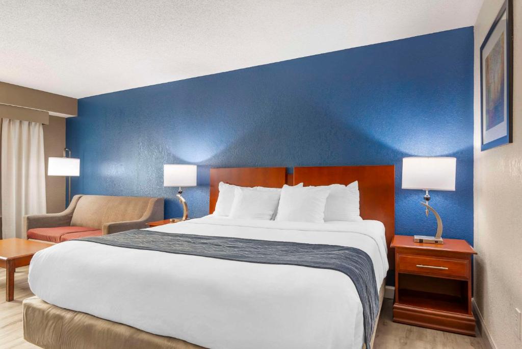 a large bed in a hotel room with a blue wall at Comfort Inn Alpharetta-Atlanta North in Alpharetta