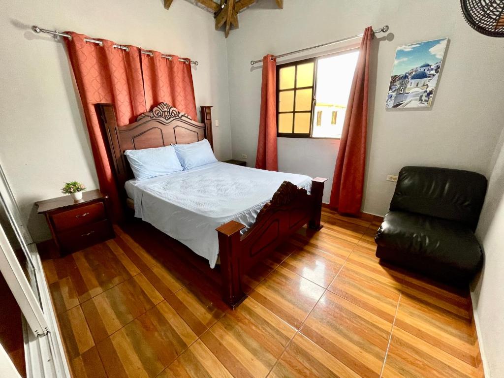 a bedroom with a bed and a chair and a window at Oasis de paz 2 in Jarabacoa