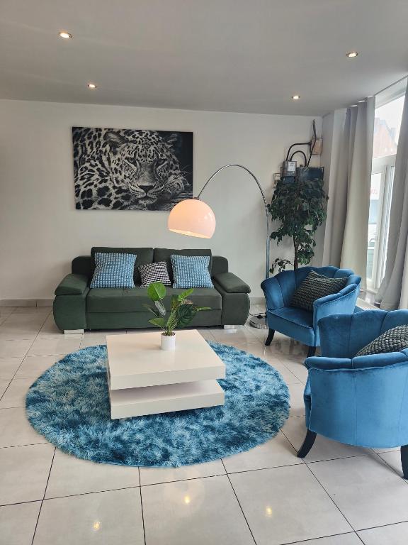a living room with a green couch and blue chairs at Bel appartement confortable Mons in Mons