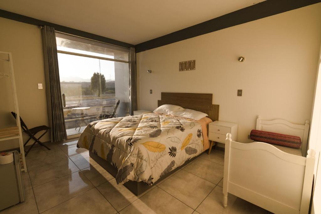 a bedroom with a bed and a large window at HOSTAL MONTALVO VALLE in Moquegua