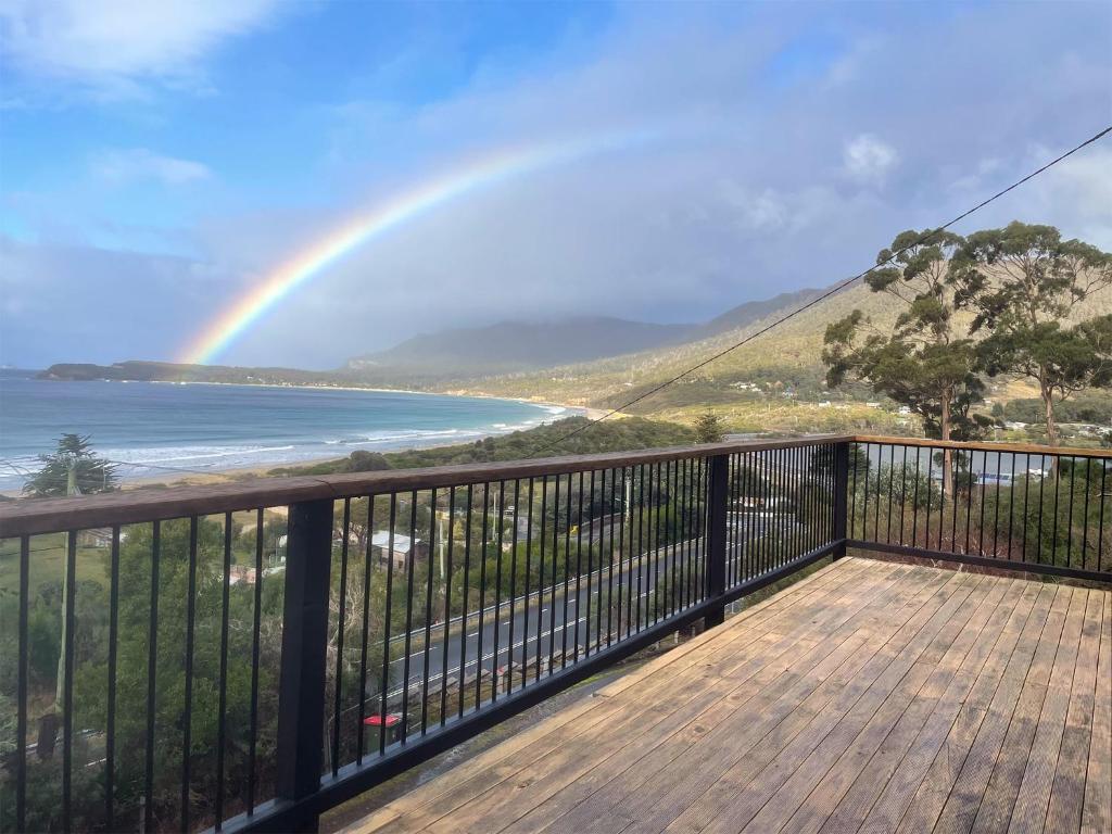 un arco iris sobre el océano con una terraza en Elevated 3BR, ocean views, pool table, Pirates Bay, en Eaglehawk Neck