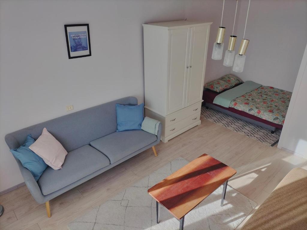 Rokiskis- jaukus butas su balkonu في روكيسكيس: غرفة معيشة مع أريكة زرقاء وخزانة