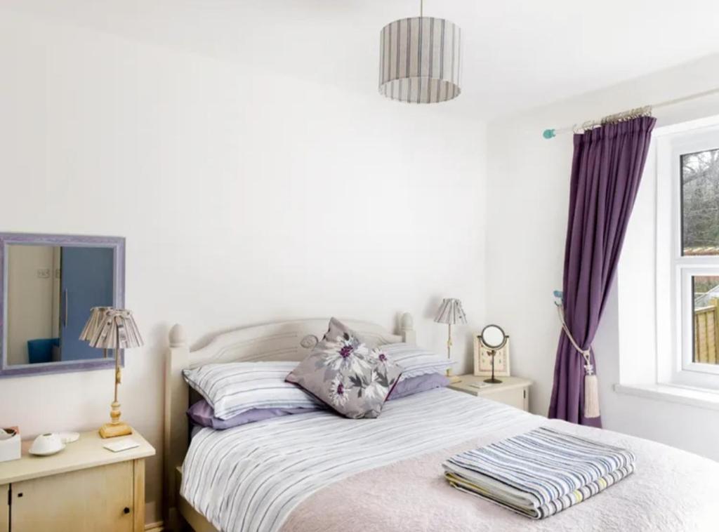 a bedroom with a bed and a window at Middleway Cottage in Saint Blazey