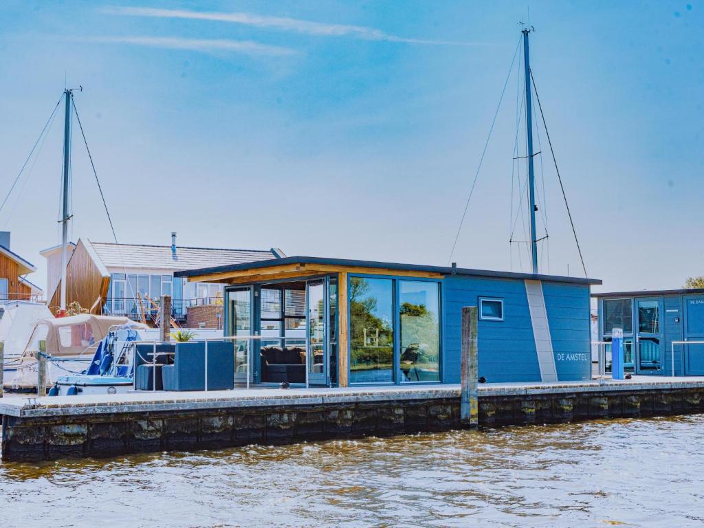 una casa azul en un muelle sobre el agua en Tiny houseboat Uitgeest I, en Uitgeest