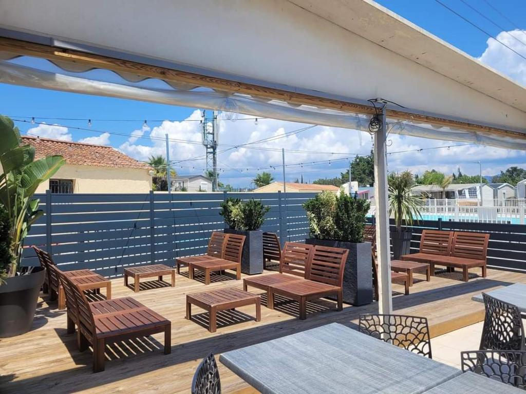 une terrasse avec des chaises et des tables en bois et une clôture dans l'établissement vacances familiales dans camping avec piscine, à Fréjus