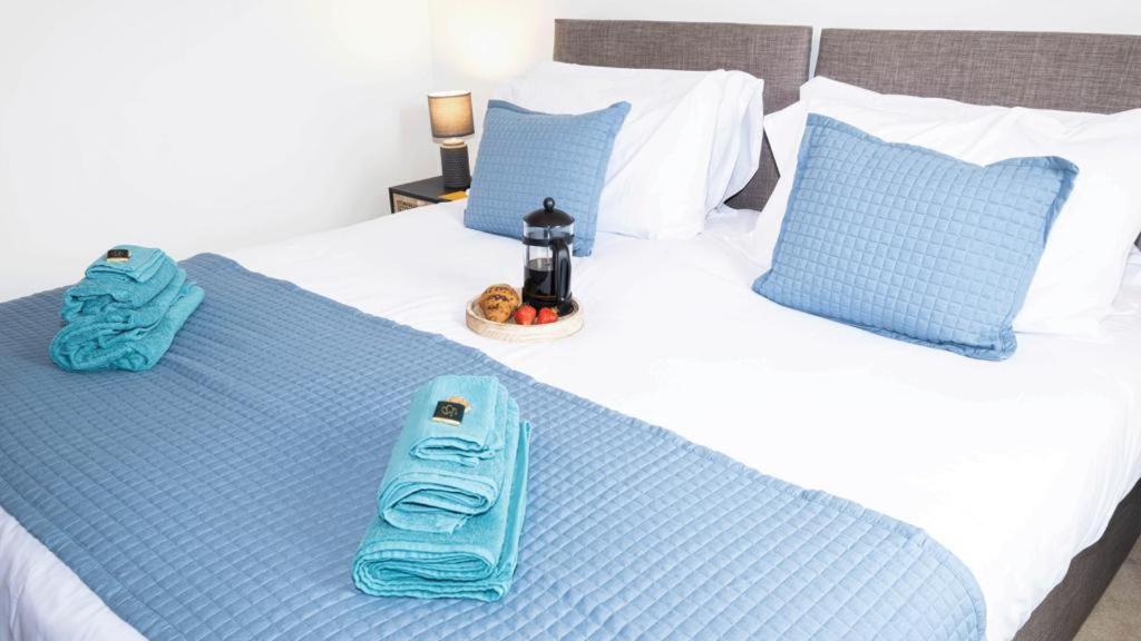 a bed with two towels and a cell phone on it at Quayside Apartments in Dundee
