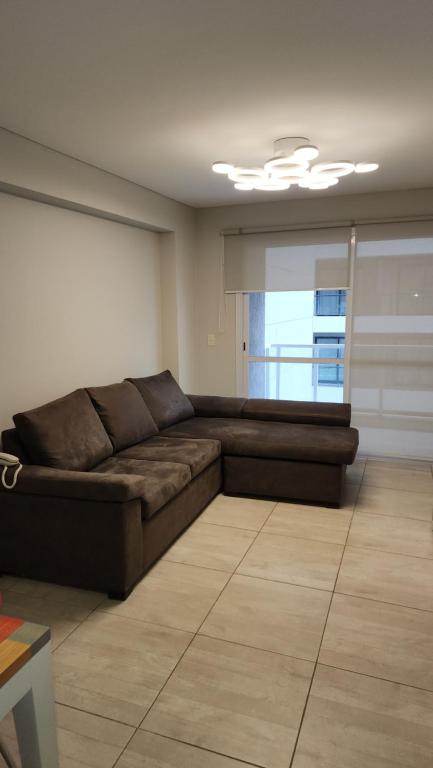 una sala de estar con un sofá marrón en una habitación en Departamento 1 dormitorio en Salta