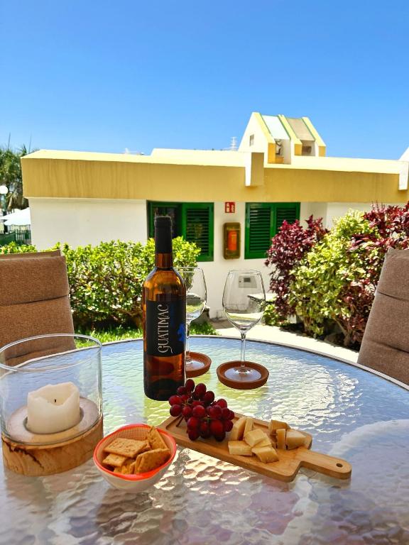 una botella de vino sentada en una mesa con queso y uvas en Bungalow Yaipe, en Maspalomas