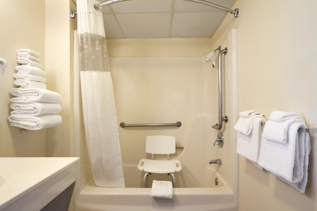 a bathroom with a shower with a white chair in it at Days Inn By Wyndham Pigeon Forge South in Pigeon Forge