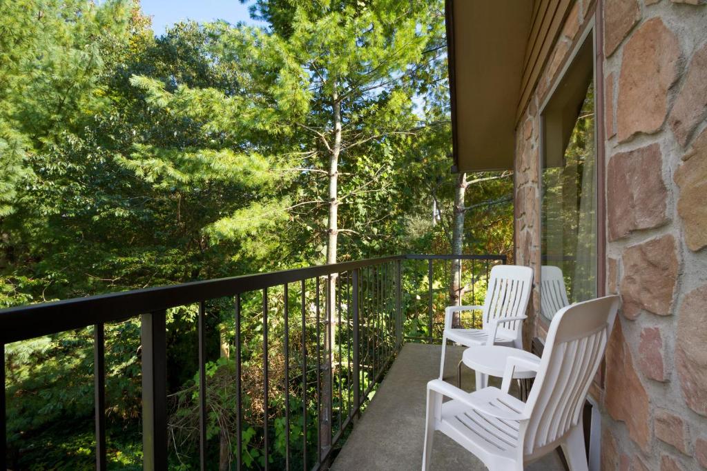 three white chairs sitting on a balcony with trees at Days Inn By Wyndham Pigeon Forge South in Pigeon Forge