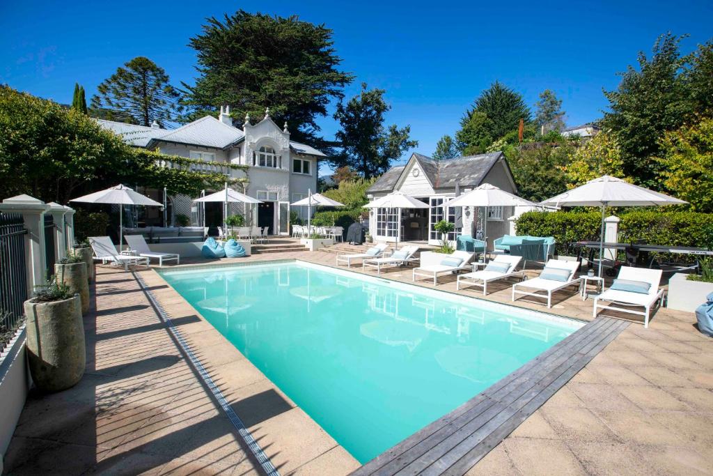 a swimming pool with chairs and umbrellas next to a house at Pihopa Retreat in Nelson