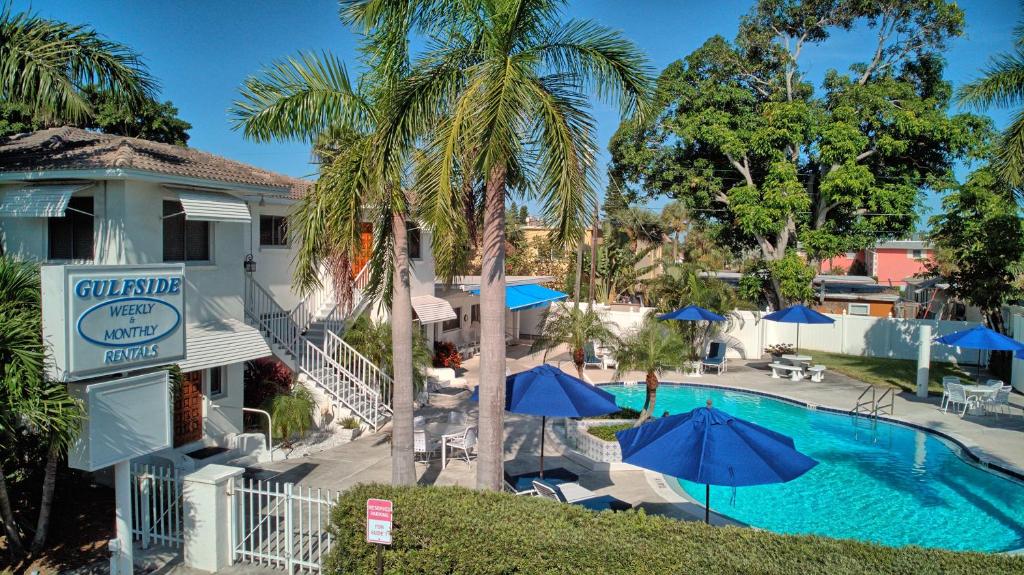 a hotel with a pool and palm trees and umbrellas at Gulfside Resort. Unit 1 in St Pete Beach