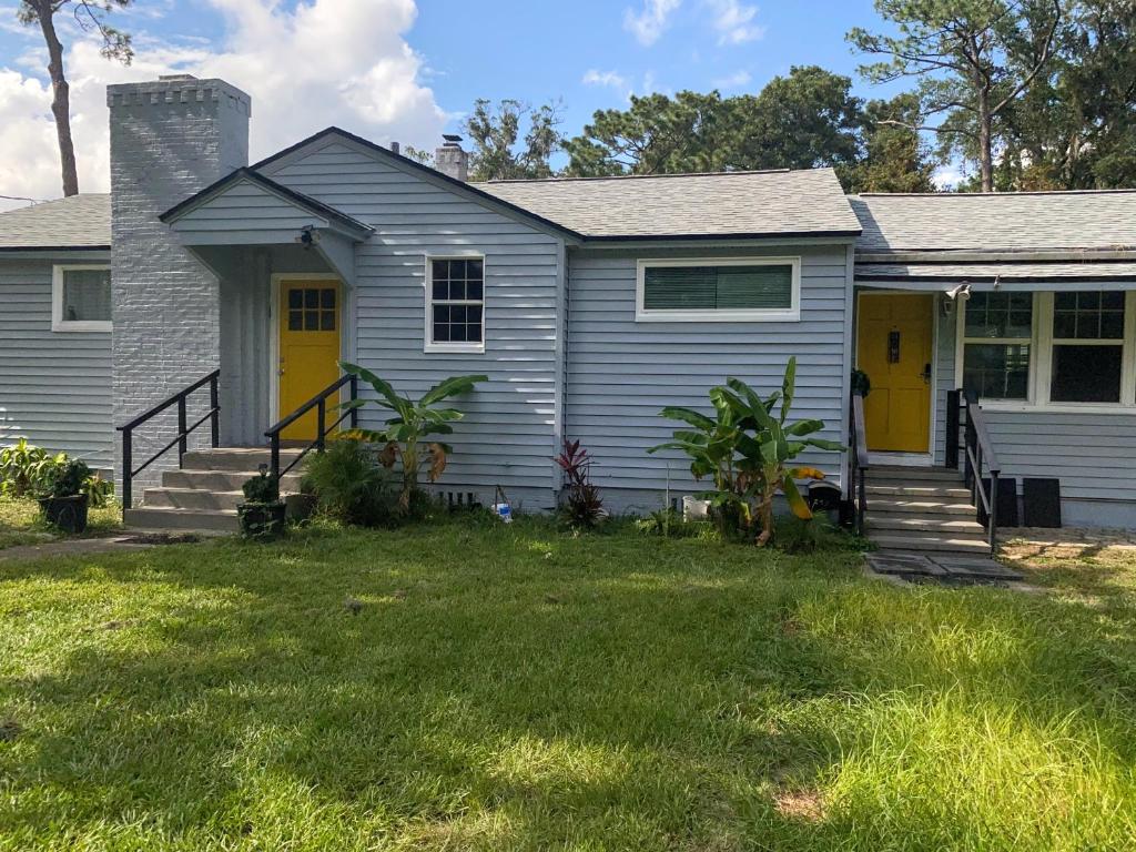 a house with a yellow door and a yard at Cozy home, King bed, 3 bedrooms,close to downtown beaches towncenter in Jacksonville