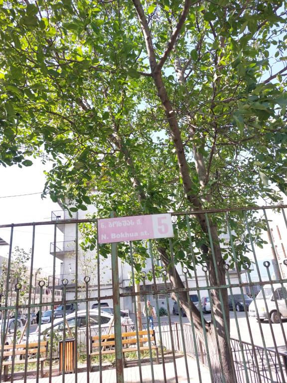 uma cerca com uma árvore em frente a um edifício em Happy em Tbilisi