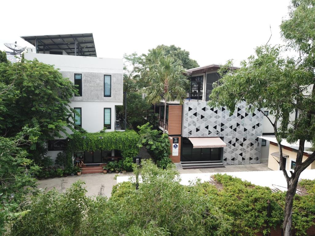 einen Blick nach außen auf ein weißes Gebäude mit Bäumen in der Unterkunft PomPom Home in Bangkok