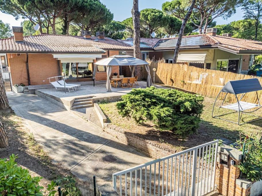 ein Haus mit einer Terrasse mit einem Tisch und einem Sonnenschirm in der Unterkunft PINETA HOUSE LIGNANO [Free Parking-Beach-Garden] in Lignano Sabbiadoro
