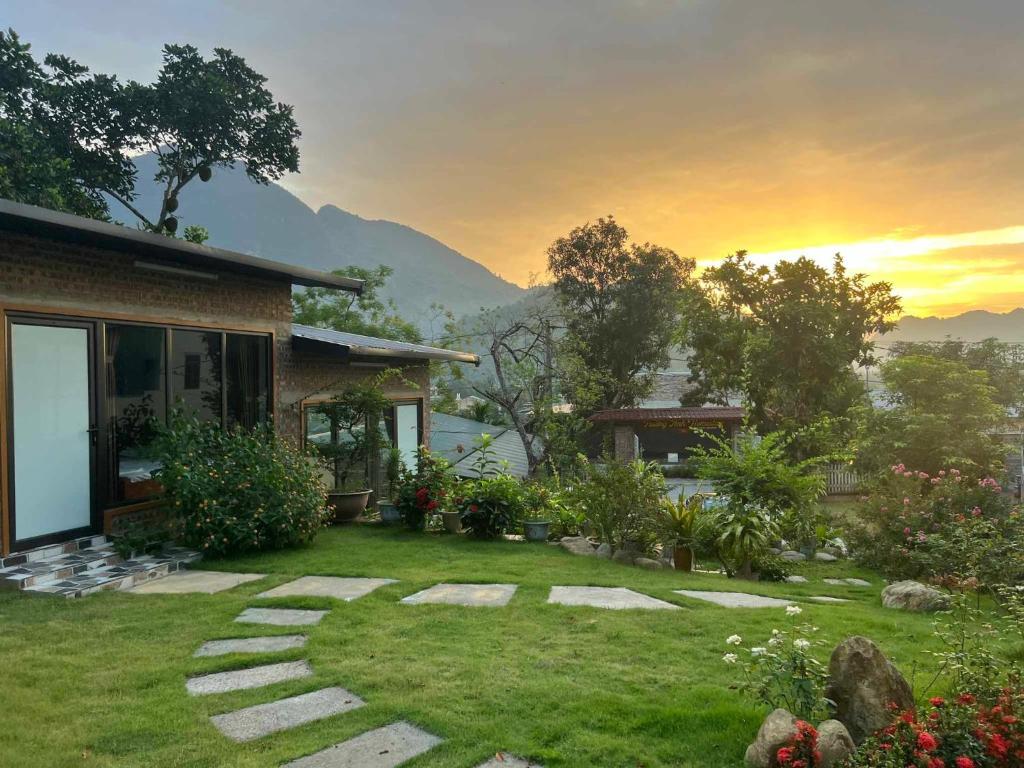 uma casa com um jardim com um pôr-do-sol ao fundo em Trường Anh Homestay Bản Tùy Hà Giang em Ha Giang