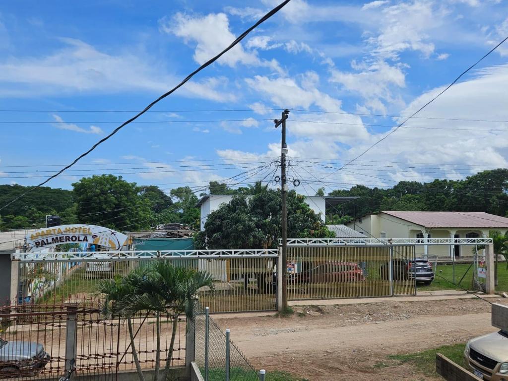 a fence in front of a yard with houses at Aparta Hotel Palmerola in Comayagua