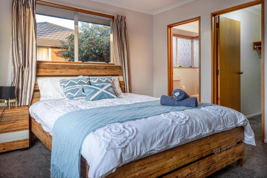 a bedroom with a large wooden bed with a window at Convenient Westfield House 3bed 2bath in Christchurch