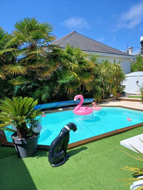una piscina con un perro negro y un flamenco rosa en maison calme avec piscine palmiers 300m de la plage pornichet centre en Pornichet