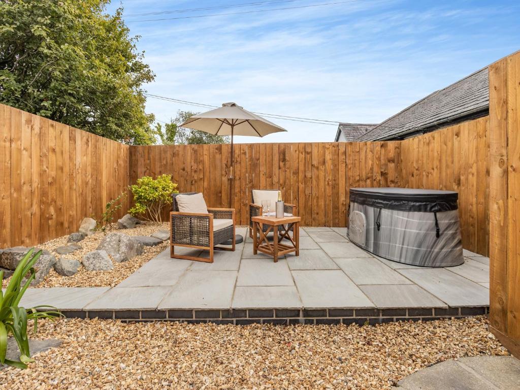 a backyard patio with a wooden fence and an umbrella at Llygad Y Dydd - Uk42788 in Bow Street