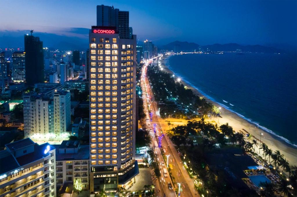 a tall building next to a beach at night at Asteria Comodo Nha Trang Hotel in Nha Trang