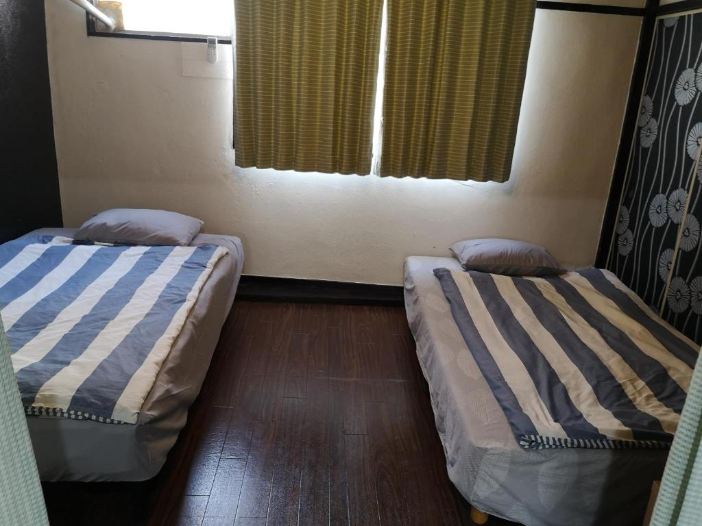 two beds sitting in a room with a window at Apartment Namba Daikoku in Osaka