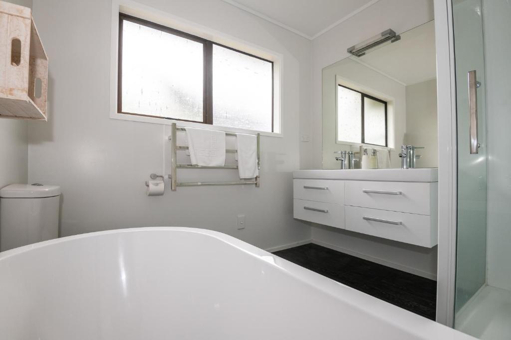 a white bathroom with a sink and a mirror at As You Do in Rotorua
