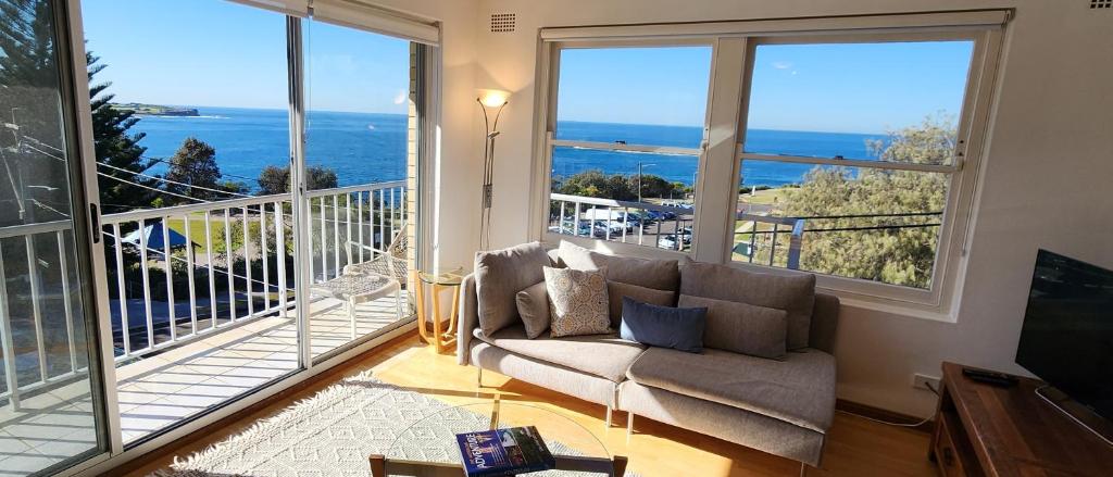 a living room with a couch and large windows at Watch The Sunrise Over Coogee 2 Bedrooms+Garage in Sydney
