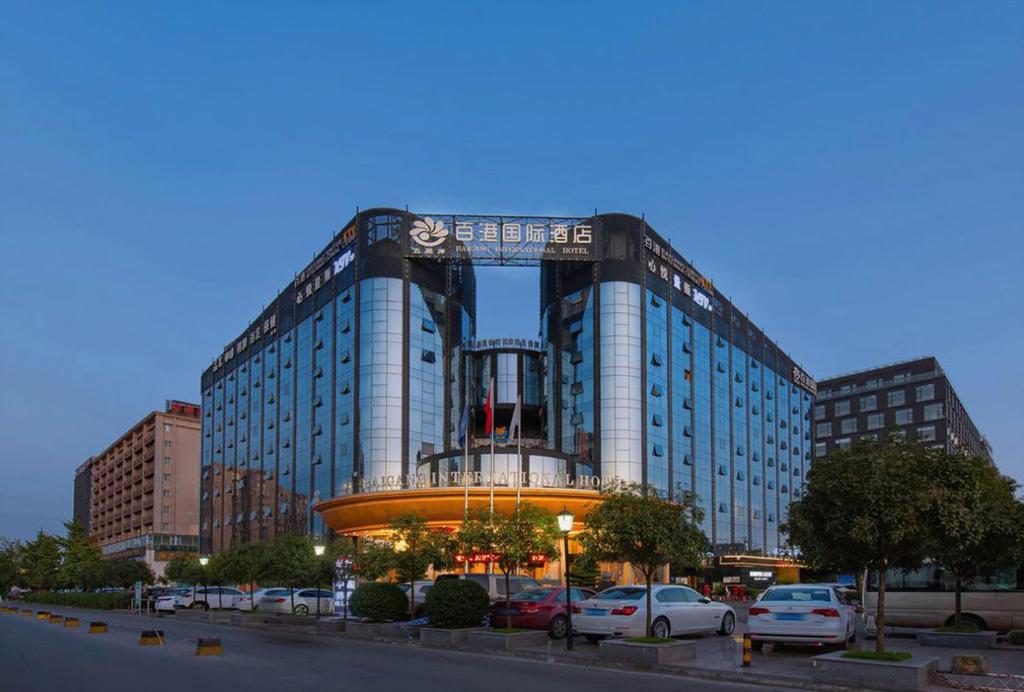 a large building with cars parked in a parking lot at Chengdu Bai Gang International Hotel in Chengdu