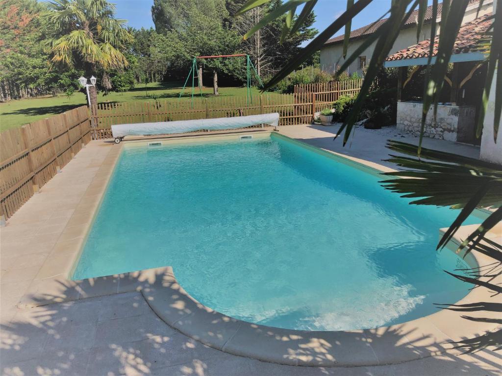 a swimming pool with blue water in a yard at Gite La Grange du Pech in Lacour