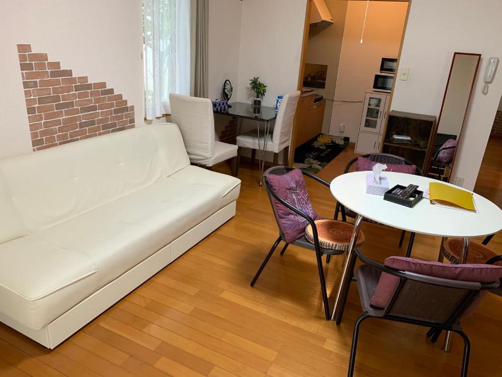 a living room with a white couch and a table at Sejour Toyohirakoen in Sapporo
