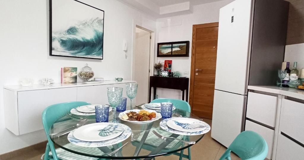 a dining room with a glass table and blue chairs at SeawaveSunGranCanaria in Telde