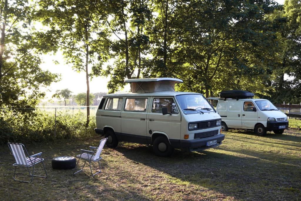 una furgoneta estacionada en un campo con dos sillas en Einfachlosmachen-BulliBus, 