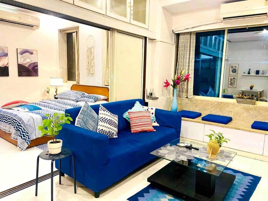 a living room with a blue couch and a bed at Arora Bhavan 1BHK-1B, Khar West by Connekt Homes in Mumbai