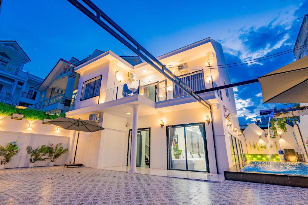 Una casa blanca con sombrillas delante de ella. en Villages Lương Văn Can, en Vung Tau