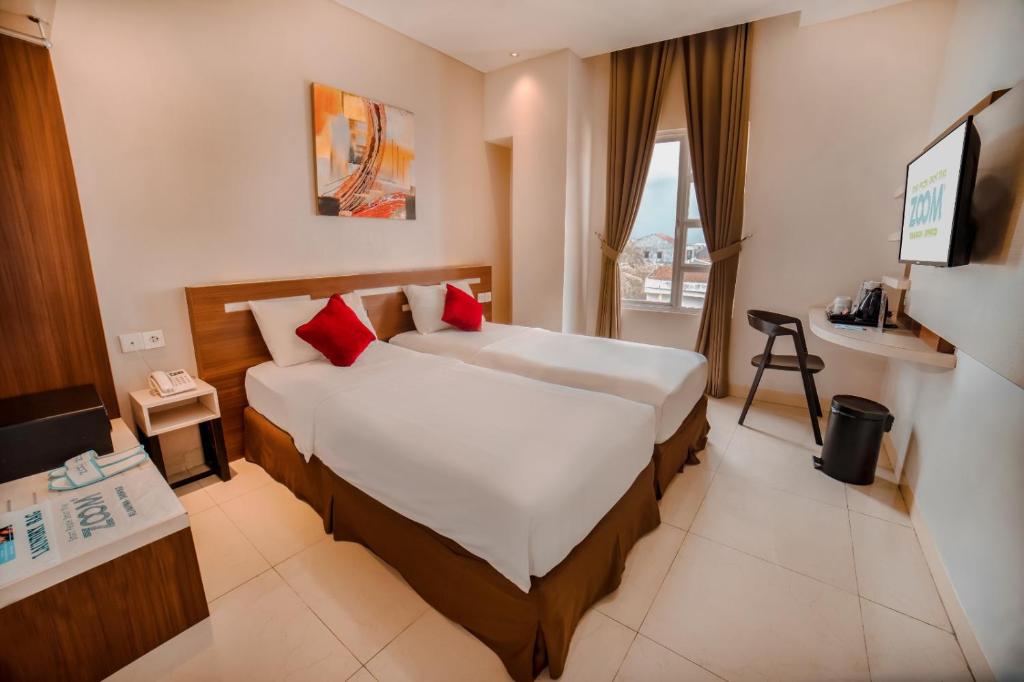 une chambre d'hôtel avec un lit et une télévision dans l'établissement Zoom Hotel Mulawarman, à Samarinda