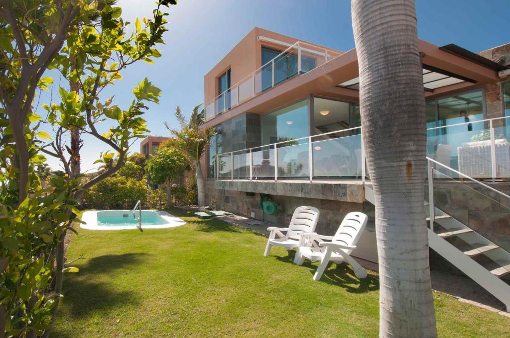 una casa con un patio con sillas y una piscina en Salobre Villas en Salobre