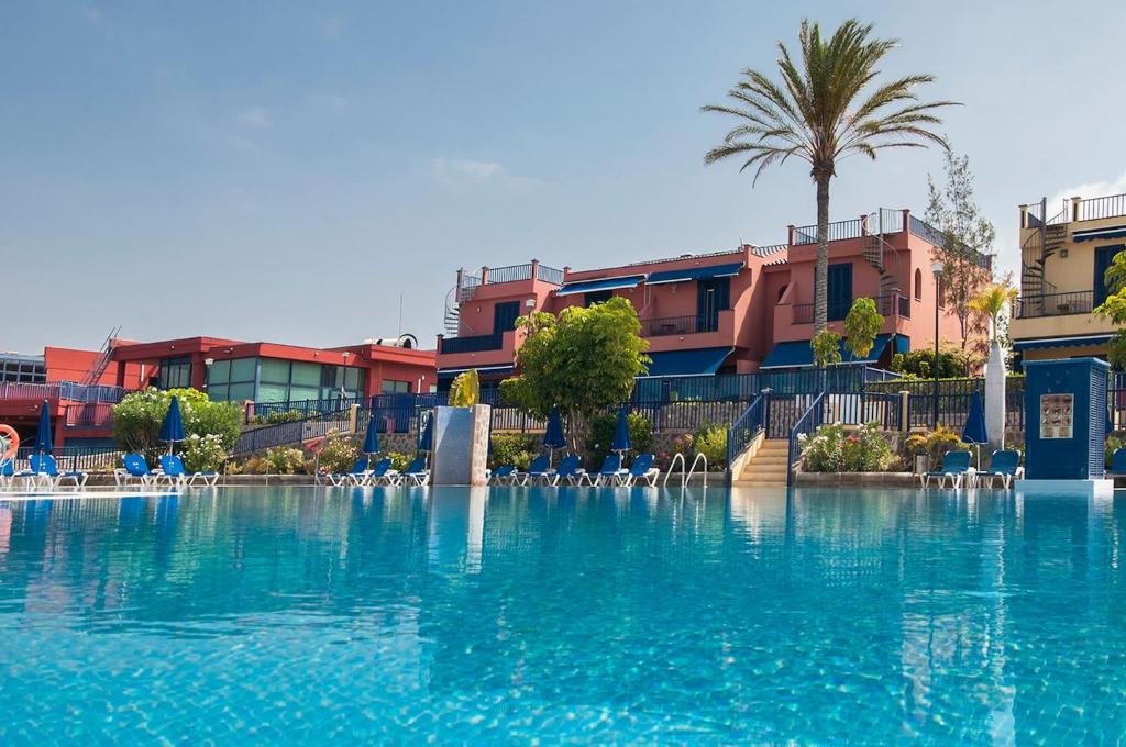 a large pool of blue water in a resort at Meloneras Suites in Meloneras