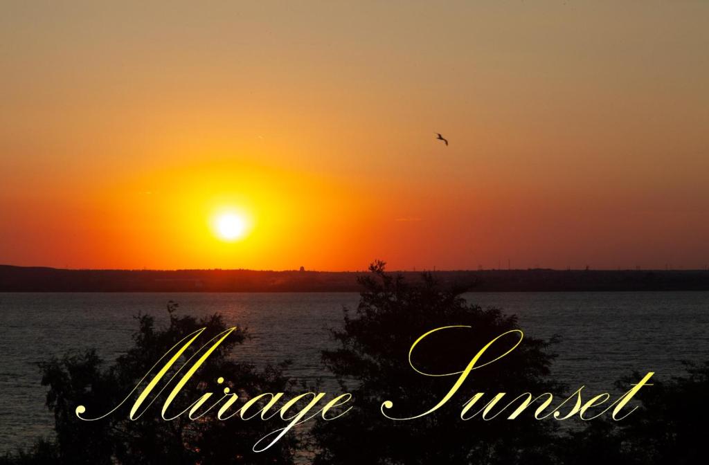 zachód słońca nad wodą z ptakiem latającym w obiekcie Aparthotel Mirage Sunset - zona Hotel Rex w Mamai
