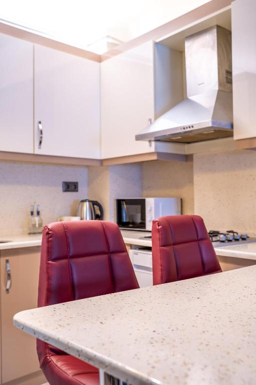 a kitchen with two red chairs at a counter at Şişli Suites in Istanbul