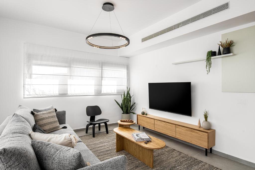 uma sala de estar com um sofá e uma televisão de ecrã plano em Mate GEORGE - By HOMY em Tel Aviv