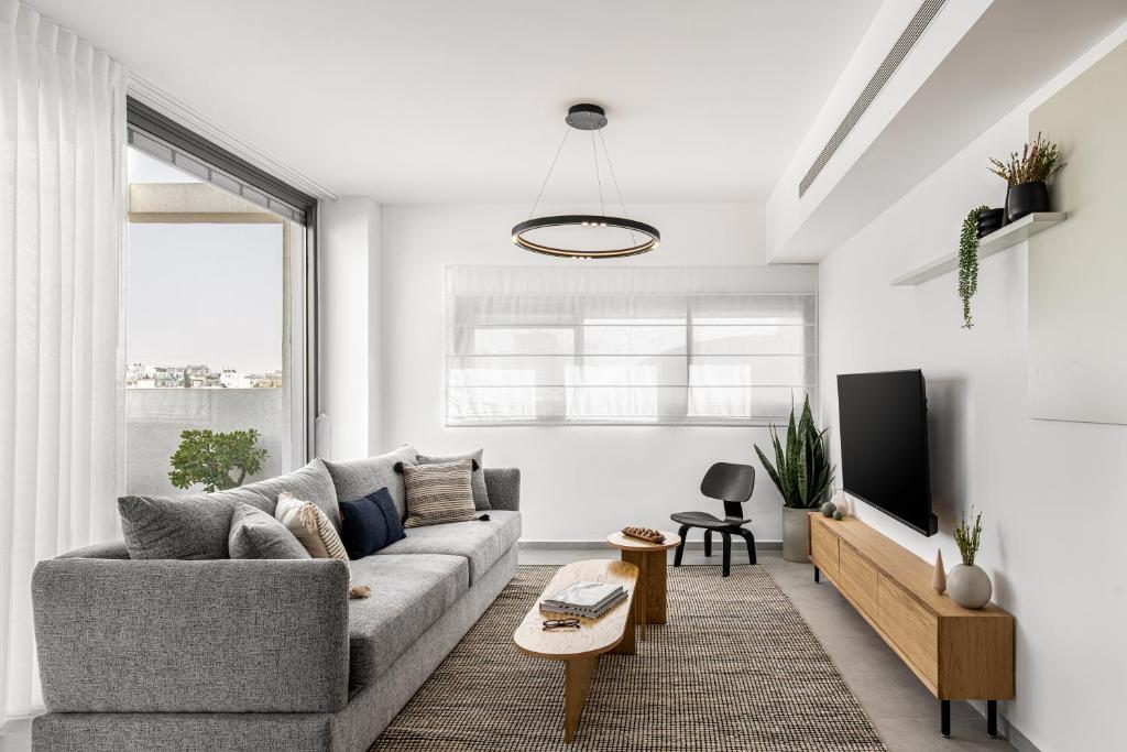 Una sala de estar con un sofá y un televisor en Mate GEORGE - By HOMY, en Tel Aviv