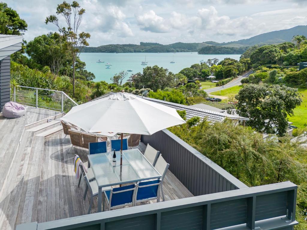 a deck with a table and chairs and an umbrella at Lavish Luxury - Parekura Bay Holiday Home in Rawhiti