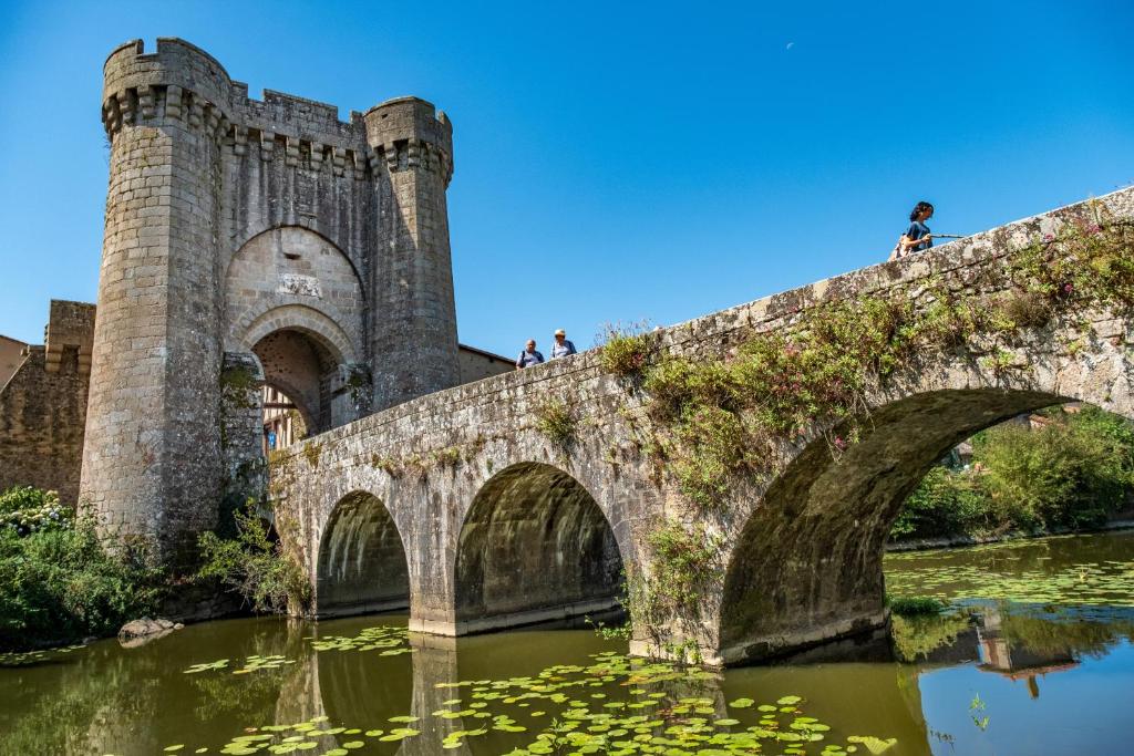 a bridge over a river with people standing on it at Gite Bin Benaise sans linge in Pamproux