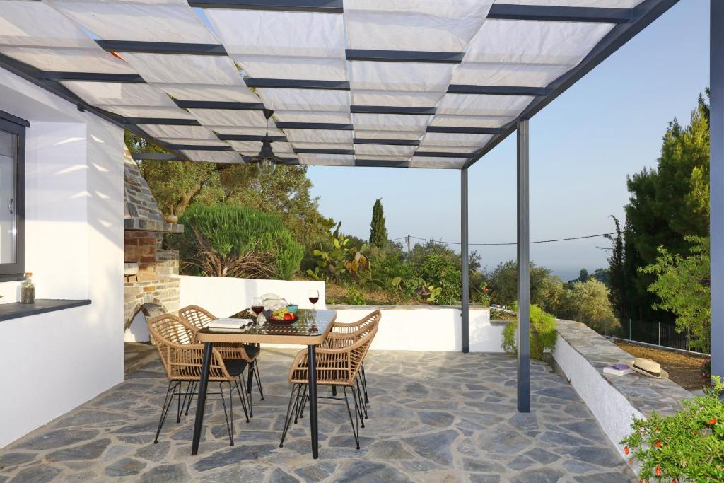 un patio con mesa y sillas bajo una pérgola en Villa John's Skopelos Stafilos, en Skopelos Town